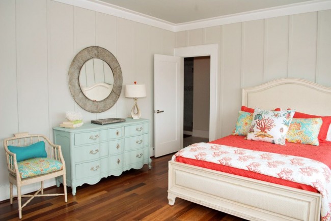 Удачное сочетание бледно-бежевого оттенка стен спальни, нежно-голубого комода и яркого кораллового текстиля