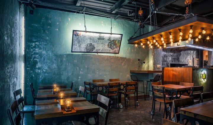 Окрашенные в изумрудный цвет, бетонные стены в интерьере ресторана