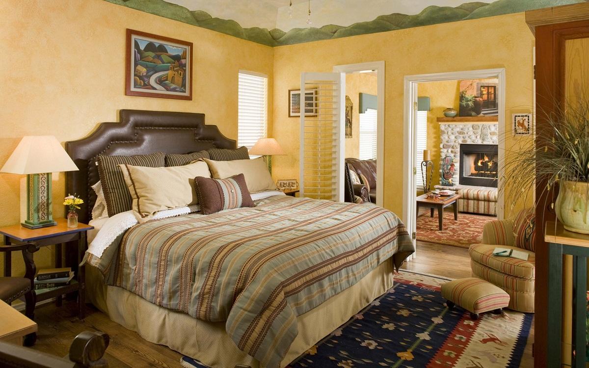 Чтобы сделать спальню уютной, расположите на кровати много подушек, а в углу комнаты поставьте мягкое кресло 