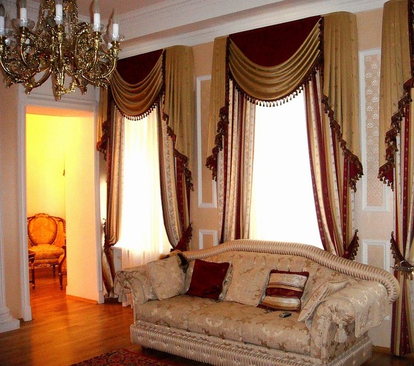 окна в клаасической гостиной оформлены золотисто-бордовыми шторами