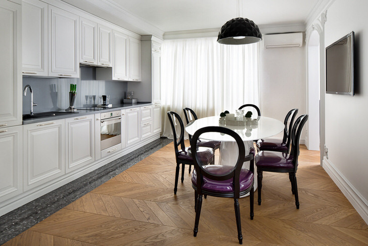 Белоснежный кухонный интерьер с акцентами темно-серого цвета в стиле эклектика. Интересны стулья с прозрачными спинками и фиолетовой мягкой обивкой.