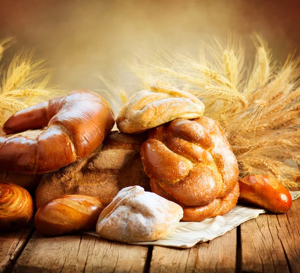 Пекарни хлеб на деревянном столе. Различные хлеб и сноп — стоковое фото