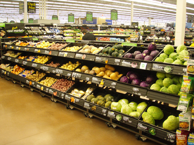 3 уровня выкладки овощей и фруктов ступенями в черных пластиковых ящиках с большим ценником