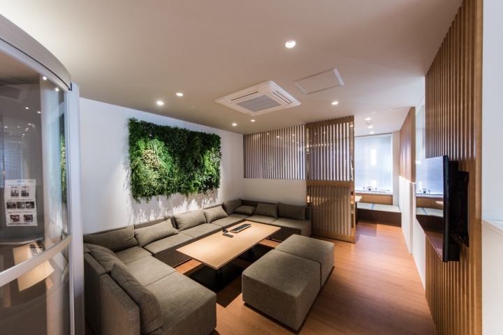 Уютное место для отдыха с зеленой композицией на стене в интерьере офиса
