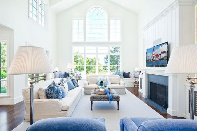 Голубые элементы в интерьере гостиной выглядят намного теплее в сочетании с мягкой мебелью и торшером сливочного цвета