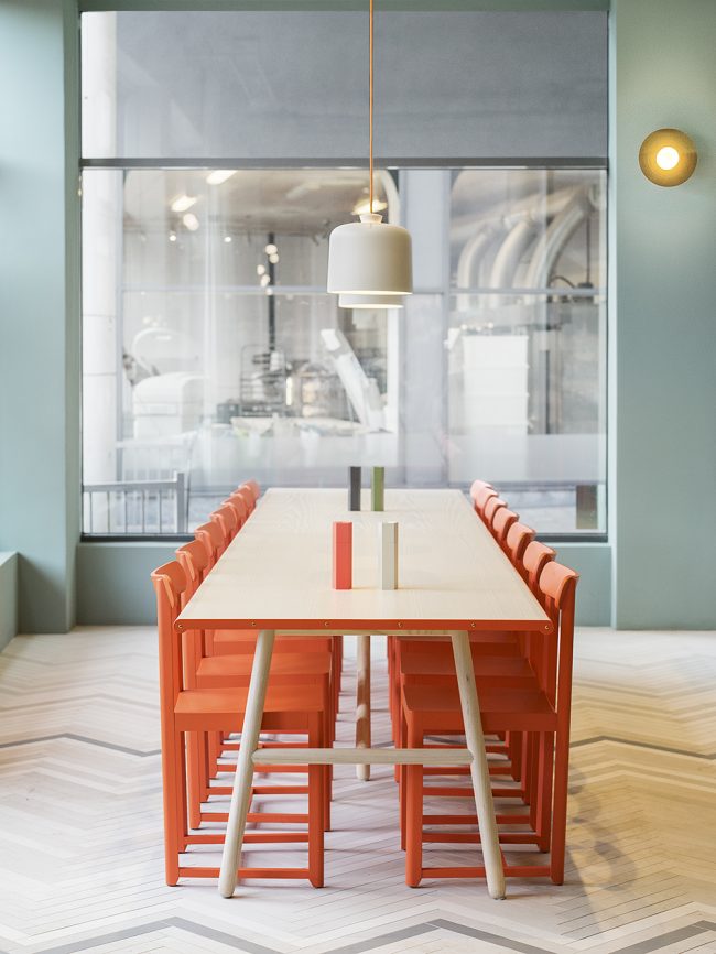 Обеденная зона светлой кухни с ярким акцентом на оранжевых стульях
