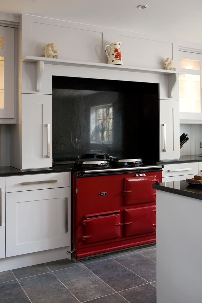 Чугунная газовая плита с красными блоками в интерьере белой кухни