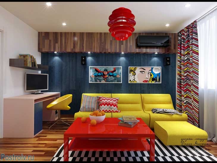 Желтый угловой диван и красный журнальный столик в гостиной, красный светильник. Фото