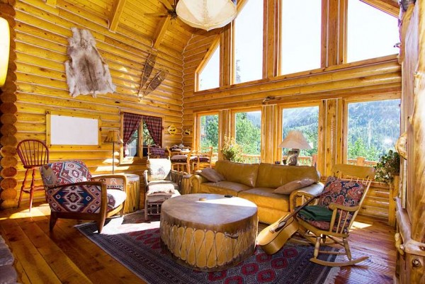 интерьер бревенчатого дома с большими окнами в бежево - желтых оттенках с деревянной и мягкой мебелью