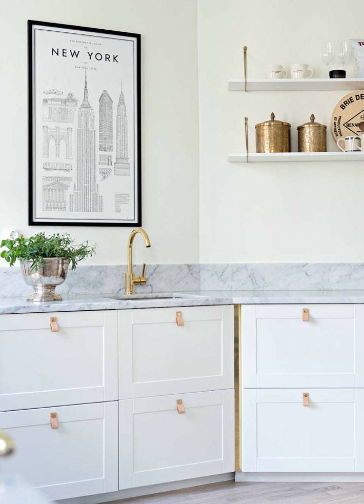 латунные смеситель и посуда на белой кухне фото