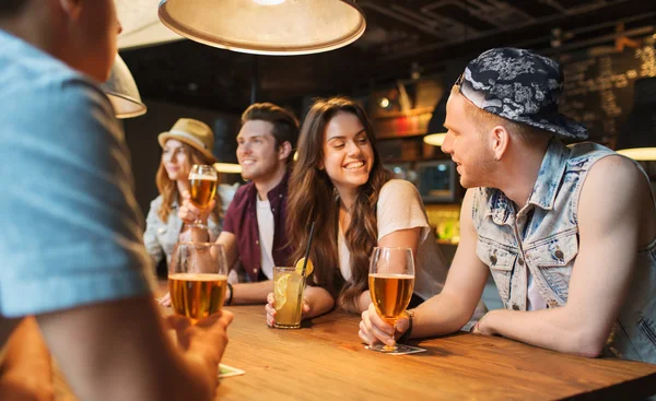 Счастливые друзья с напитками, говорить в баре или пабе — стоковое фото