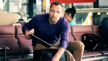 Пассажир с ноутбуком, сидящим в приемной аэропорта — стоковое видео