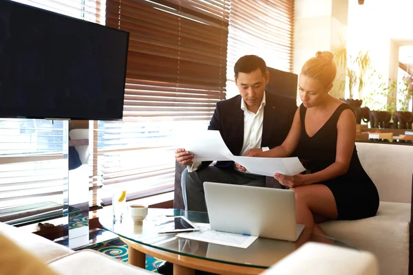 Young man and woman working together with paper documents before meeting with partners — стоковое фото