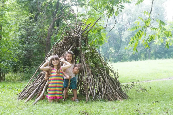 Дети играют возле дома деревянной палочкой — стоковое фото
