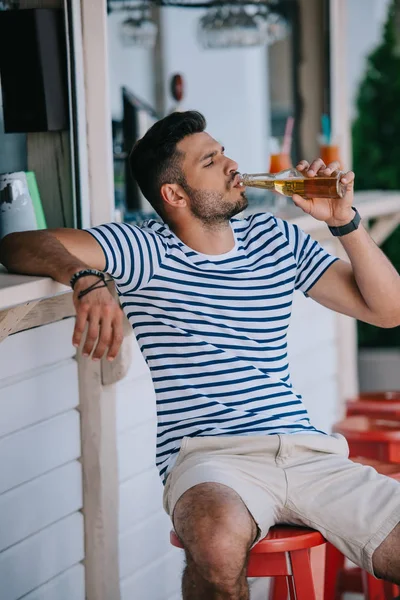 Красивый Молодой Человек Пить Пиво Стеклянной Бутылки Сидя Баре Пляже — стоковое фото